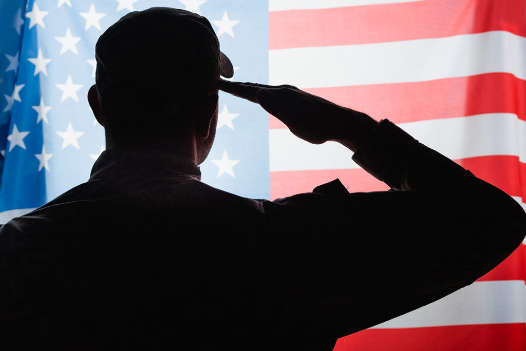 Silhouette of a soldier saluting the American flag, symbolizing honor and service.