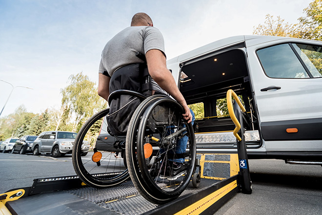 Man in a wheelchair using a ramp to enter an accessible van.