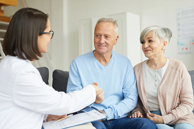 Older couple meeting with a medical professional in a home setting.