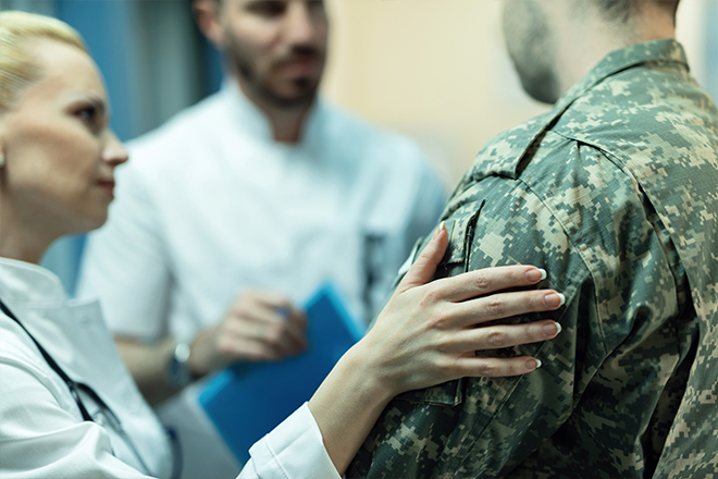 Doctor placing a supportive hand on a soldier’s shoulder during a consultation