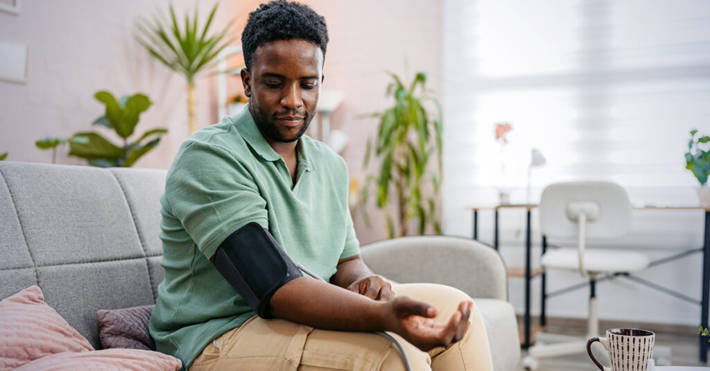 Veteran checking blood pressure at home, self-monitoring and aware of hypertension.