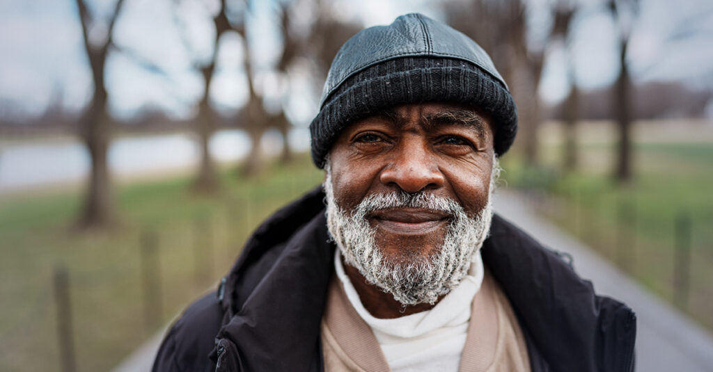 Older veteran smiling outdoors, confident after addressing hypertension.