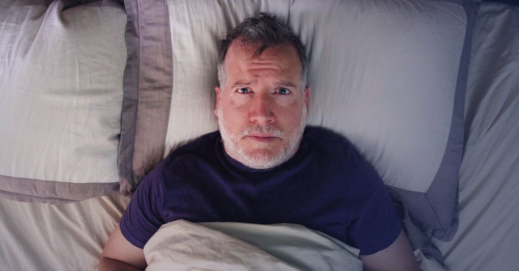 Veteran lying awake at night struggling with insomnia.