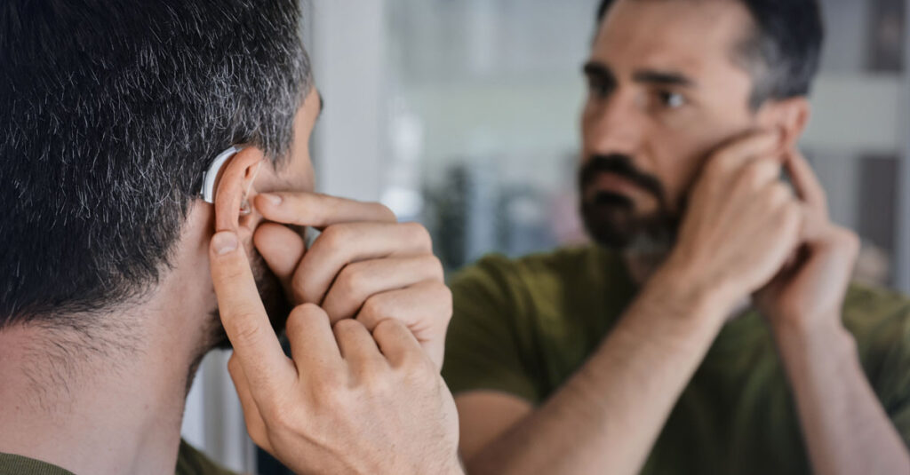 Veteran adjusting hearing aid.