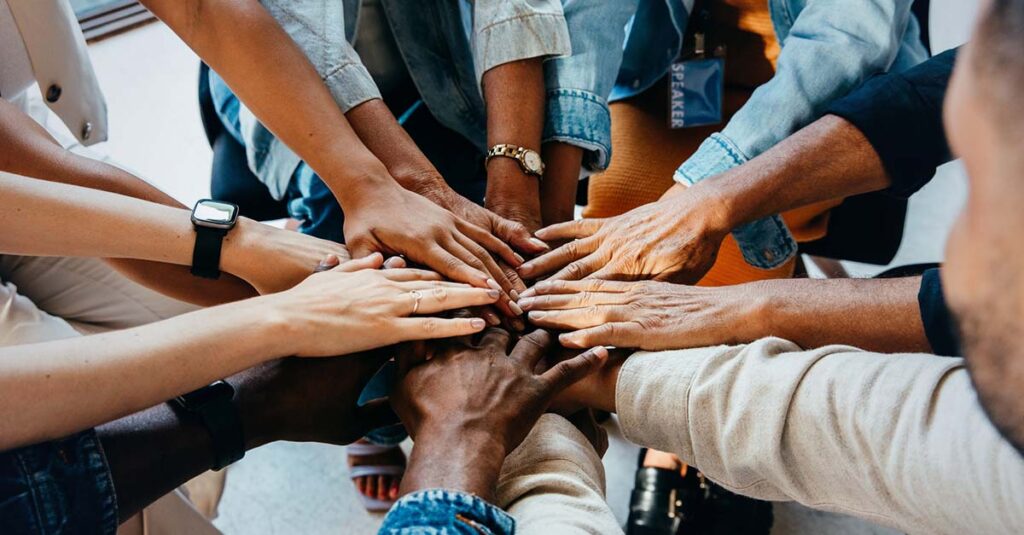 Gathering of people centering hands.